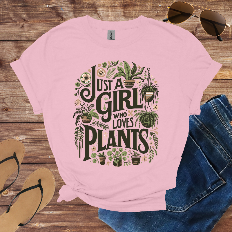 Pink t-shirt with 'Just a Girl Who Loves Plants' design on a wooden surface with sunglasses, jeans, and sandals.