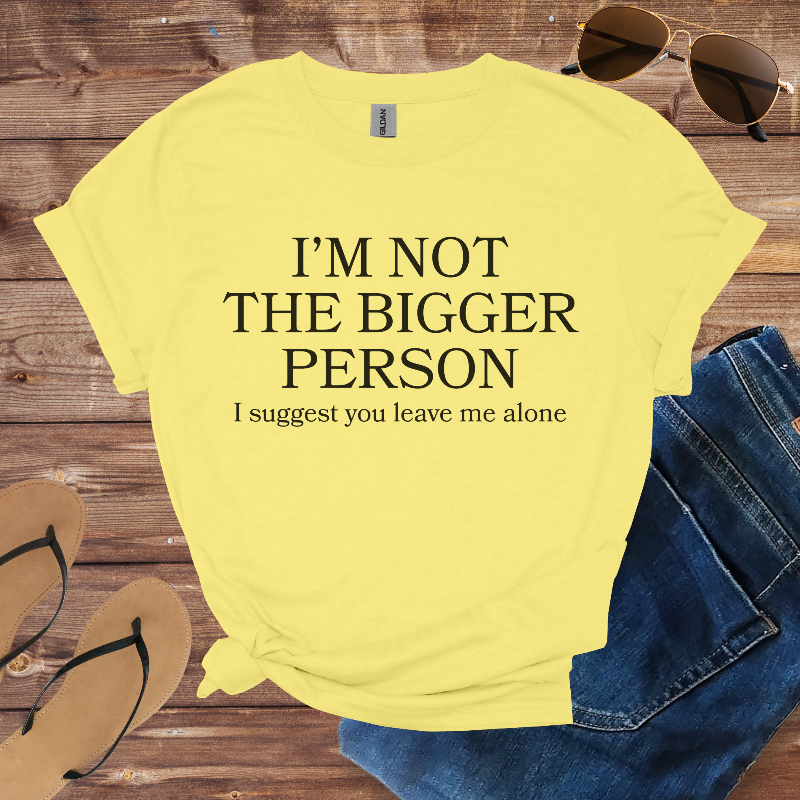 Yellow t-shirt with humorous text on a wooden surface with sunglasses and jeans.
