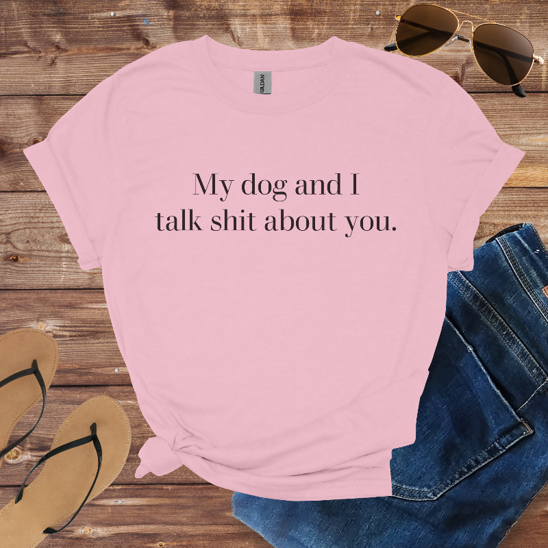 Pink t-shirt with humorous text on a wooden surface with sunglasses, jeans, and flip-flops.