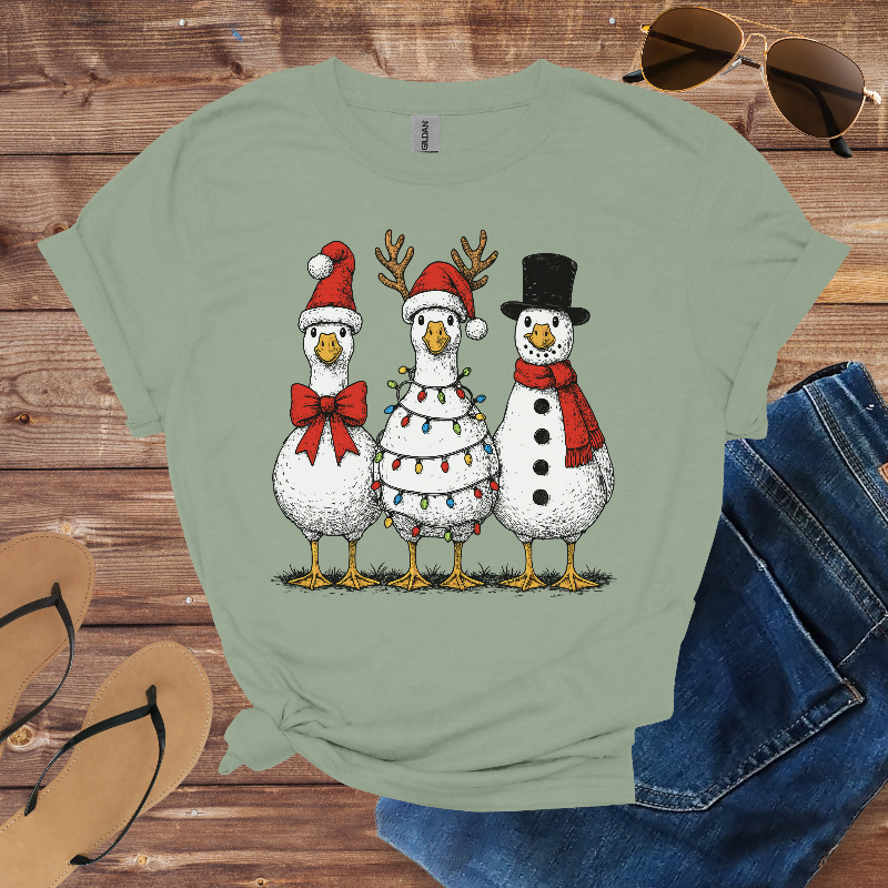 Green t-shirt with Christmas-themed design of ducks and a snowman on a wooden surface.