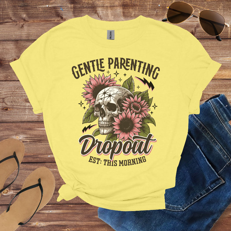 Yellow t-shirt with skull and floral design on a wooden surface with sunglasses, jeans, and sandals.