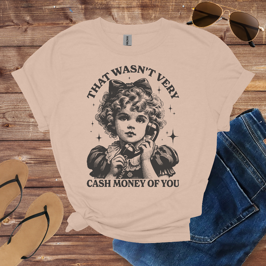 Beige t-shirt with vintage-style graphic and text on a wooden surface with sunglasses, jeans, and sandals.