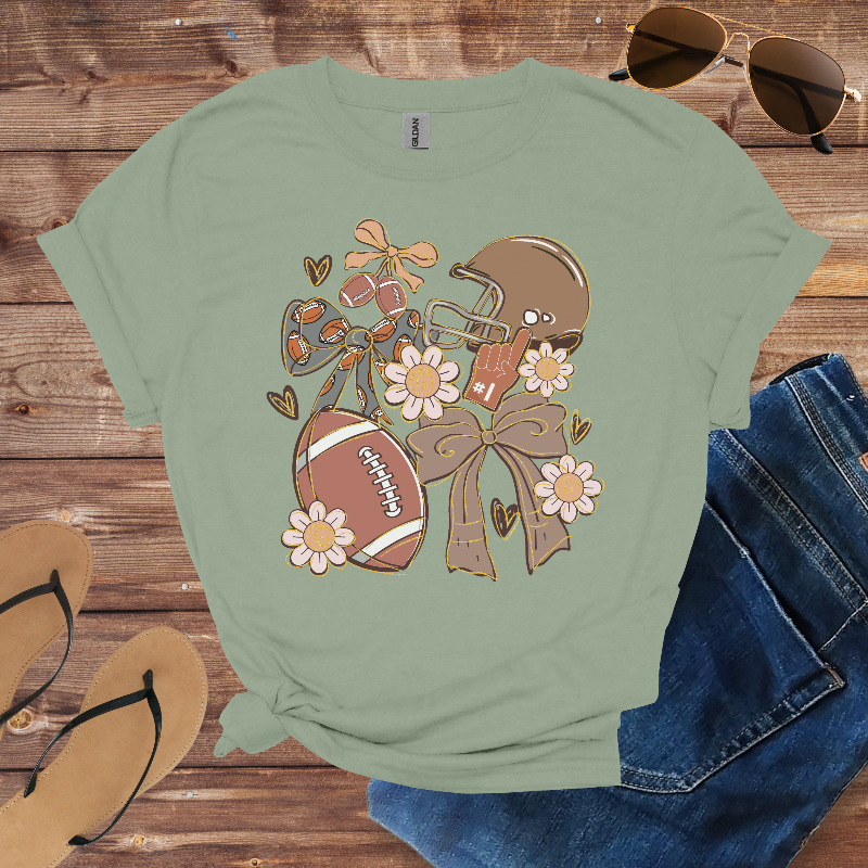 Green t-shirt with football and helmet design on a wooden surface with sunglasses and jeans.