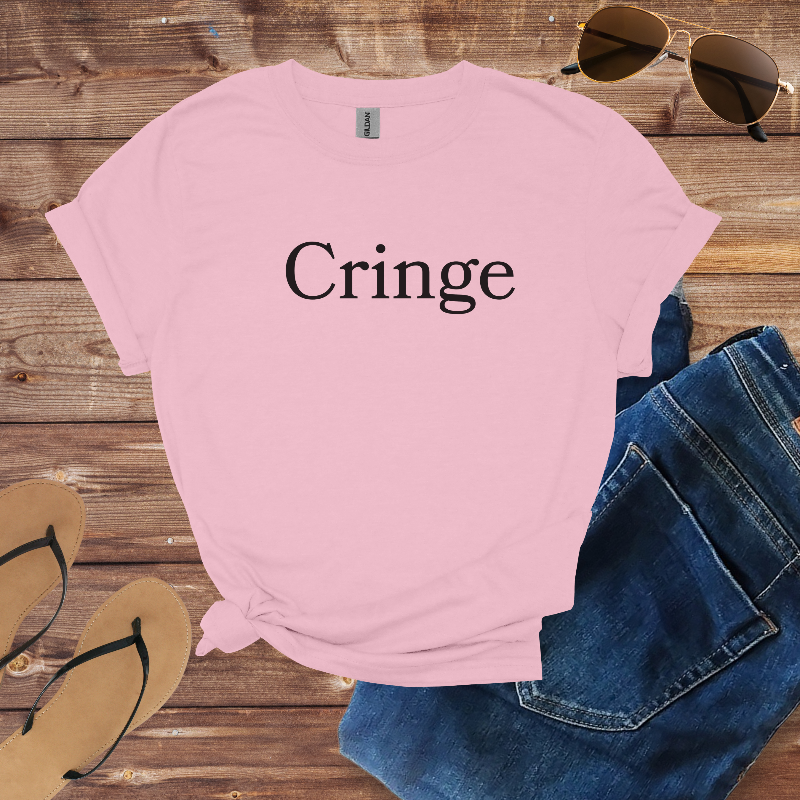 Pink t-shirt with 'Cringe' text on a wooden surface with sunglasses and jeans.