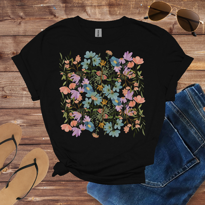 Black t-shirt with floral design, sunglasses, jeans, and sandals on a wooden surface