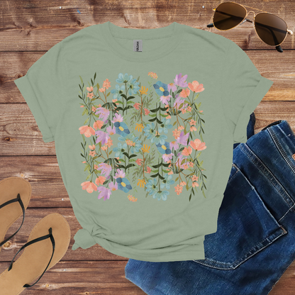 Green t-shirt with floral design, sunglasses, jeans, and sandals on a wooden surface