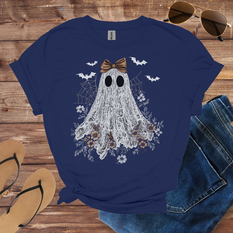 Navy blue t-shirt with a ghost design on a wooden surface with sunglasses, jeans, and sandals.