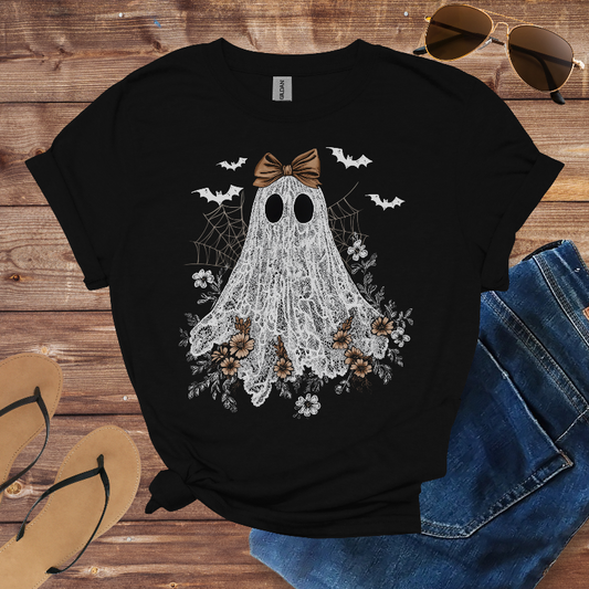 Black t-shirt with a ghost design on a wooden surface with jeans and sandals.