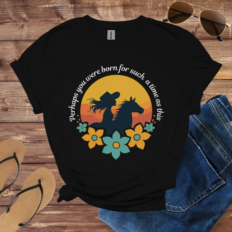 Black t-shirt with a horse and floral design on a wooden surface with sunglasses, jeans, and sandals.
