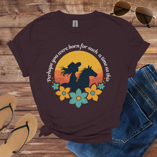 Brown t-shirt with horse graphic and text on a wooden surface with sunglasses, flip-flops, and jeans.