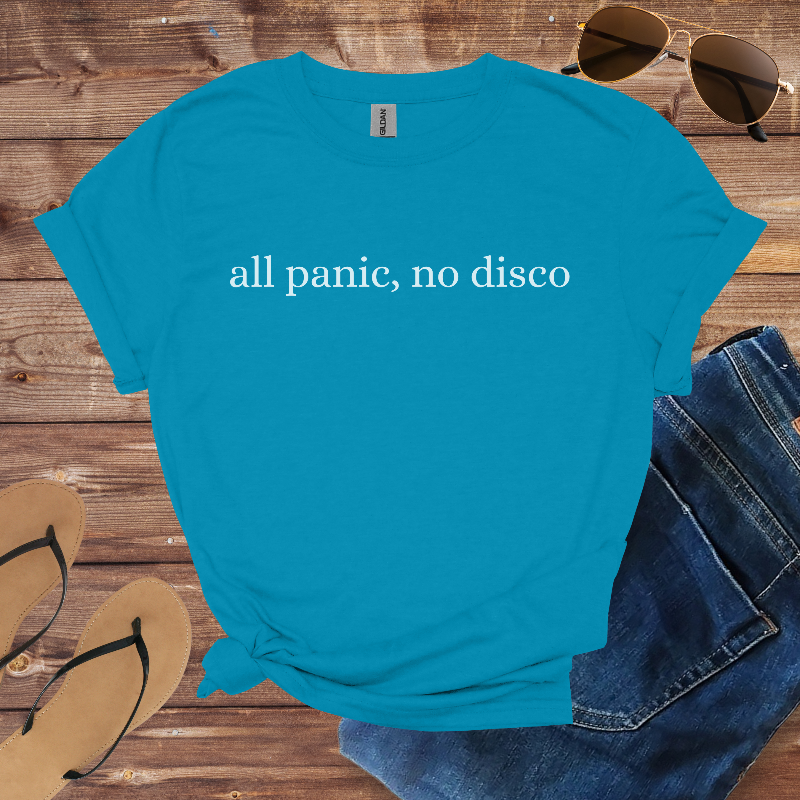 Blue t-shirt with 'all panic, no disco' text on a wooden surface with sunglasses, jeans, and flip-flops.