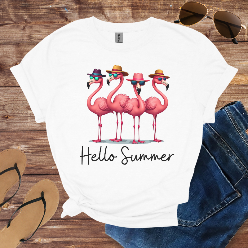 White t-shirt with flamingo design and 'Hello Summer' text on a wooden surface with sunglasses, jeans, and sandals.