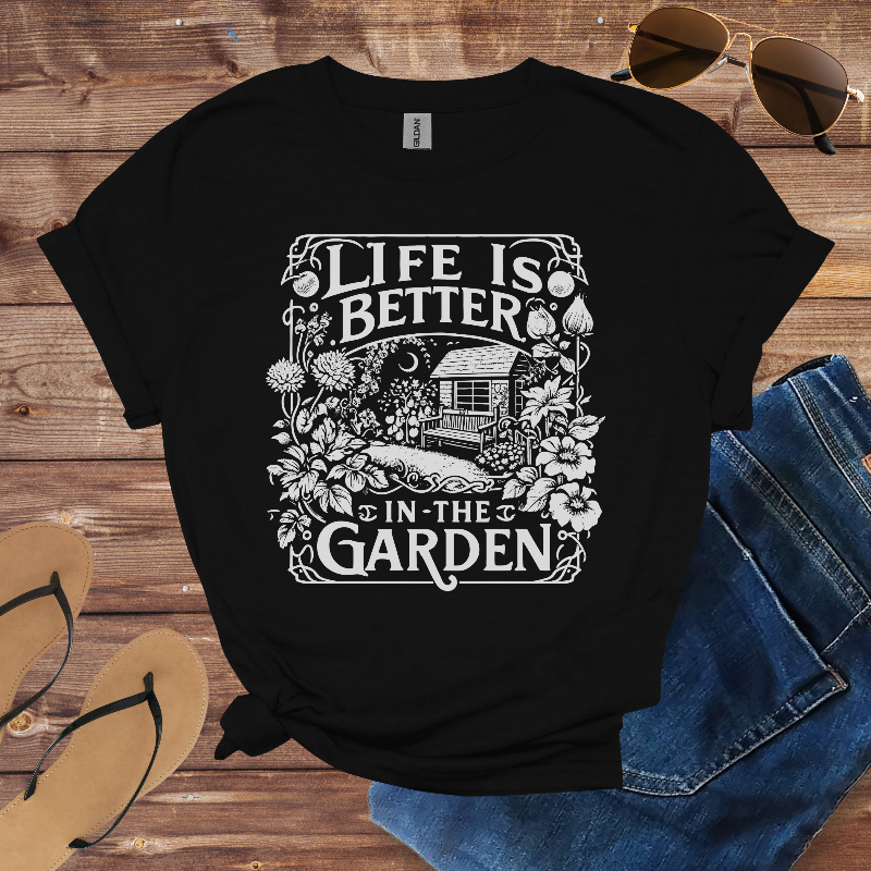 Black t-shirt with 'Life is Better in the Garden' design on a wooden surface with sunglasses, jeans, and sandals.