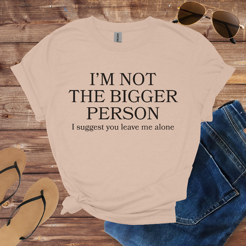 Beige t-shirt with humorous text on a wooden surface with sunglasses, jeans, and flip-flops.
