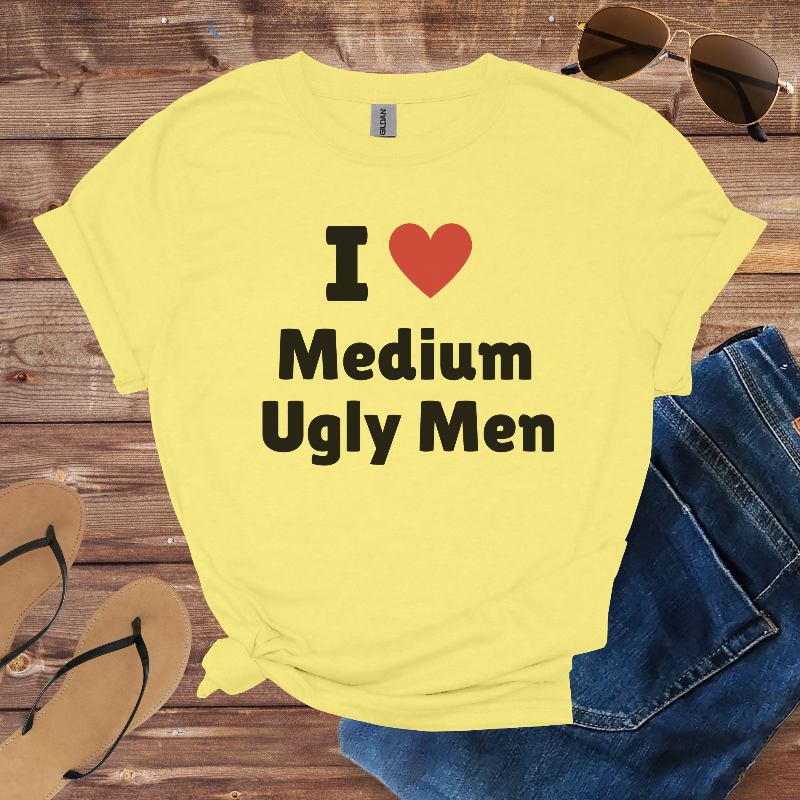 Yellow t-shirt with 'I ❤️ Medium Ugly Men' text on a wooden surface with sunglasses, jeans, and sandals.