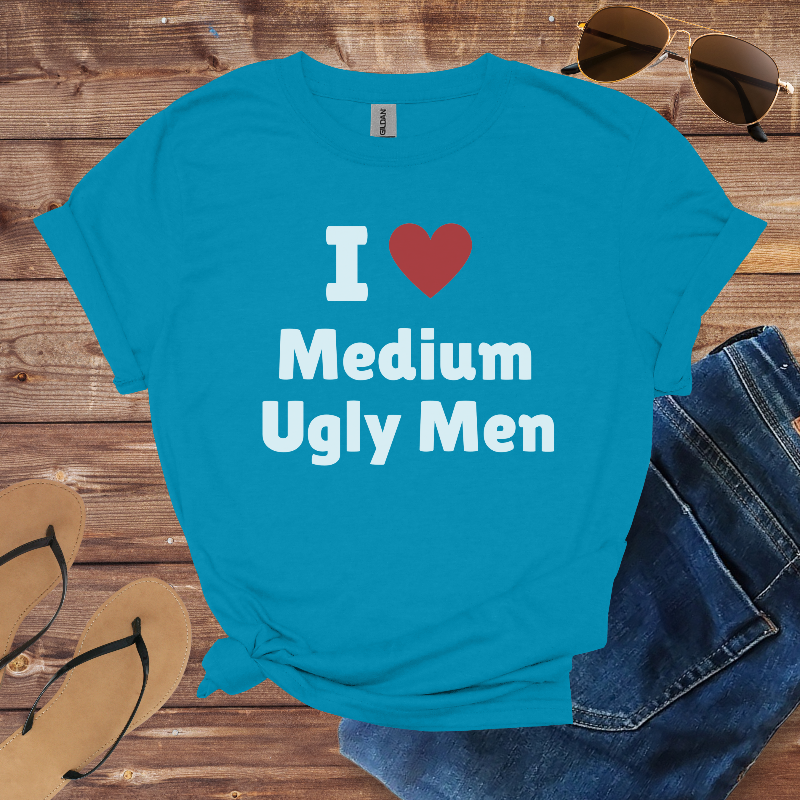 Blue t-shirt with 'I ❤️ Medium Ugly Men' text on a wooden surface with sunglasses, jeans, and sandals.