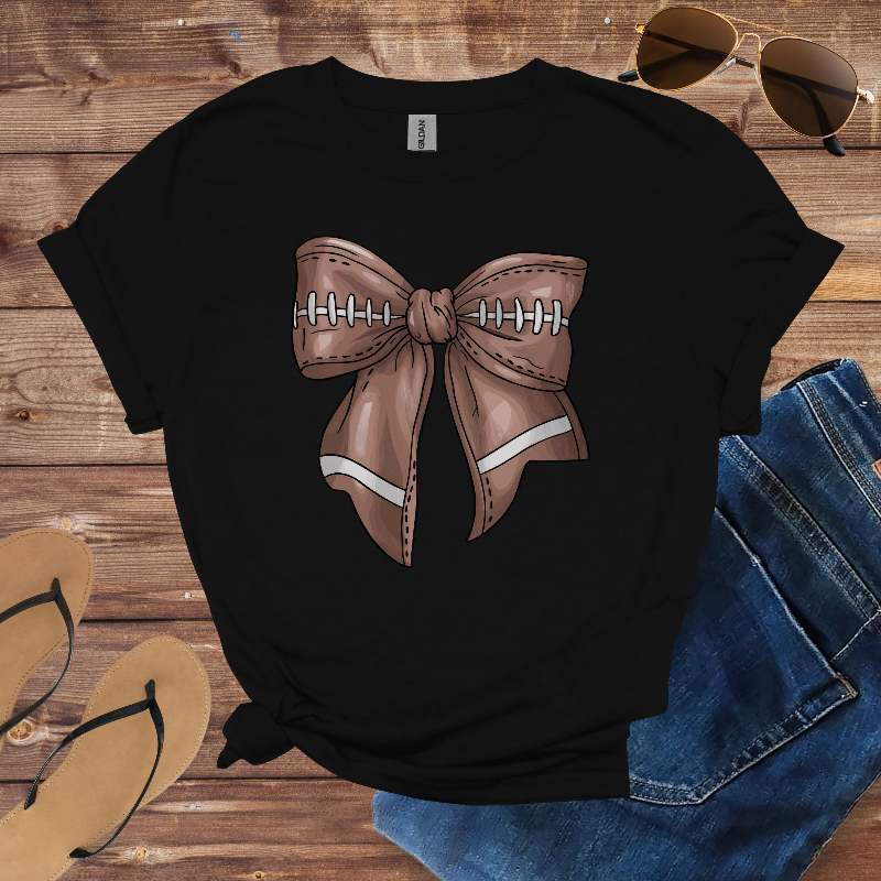 Black t-shirt with a brown bow design on a wooden surface with sunglasses and jeans.
