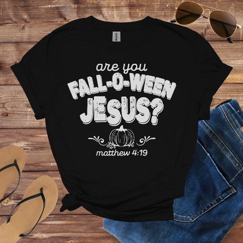 Black t-shirt with 'are you Fall-o-ween Jesus?' text on a wooden surface with sunglasses and jeans.