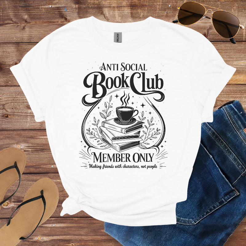 White t-shirt with 'Anti Social Book Club' design on a wooden surface with sunglasses, jeans, and sandals.