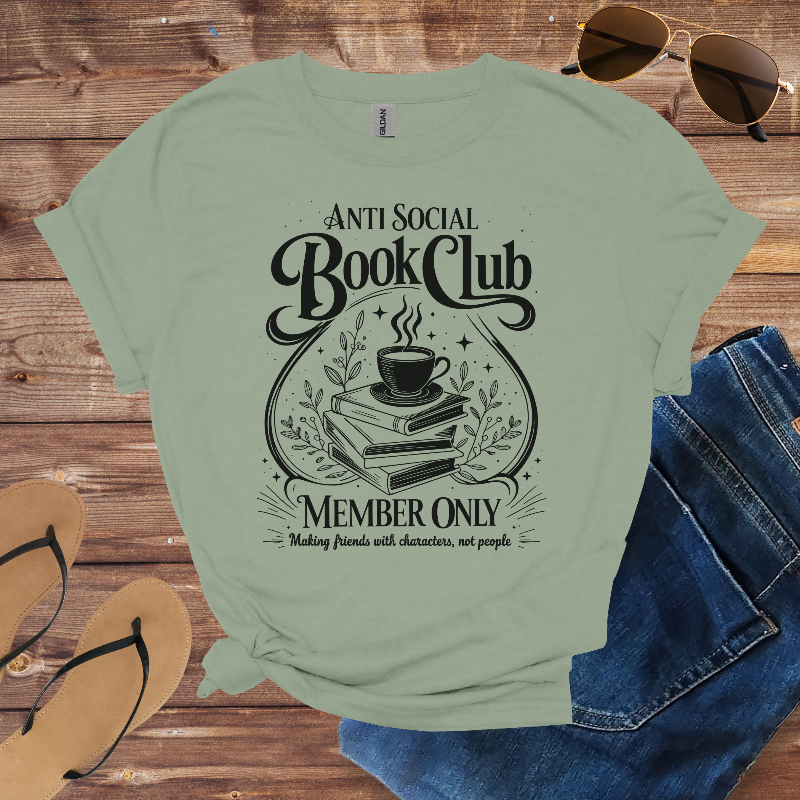 Light green t-shirt with 'Anti Social Book Club' design on a wooden surface with sunglasses, jeans, and sandals.