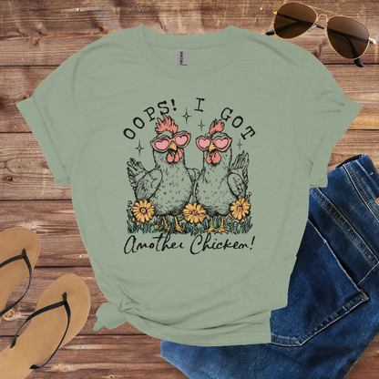 Green t-shirt with chicken graphic and text on a wooden surface with sunglasses, jeans, and sandals.