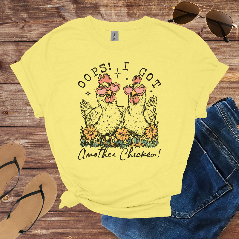 Yellow t-shirt with chicken graphic and text on a wooden surface with sunglasses and jeans.
